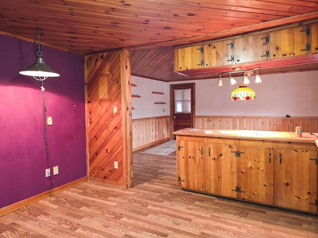 kitchen featuring decorative light fixtures, light hardwood / wood-style flooring, wooden ceiling, and wood walls