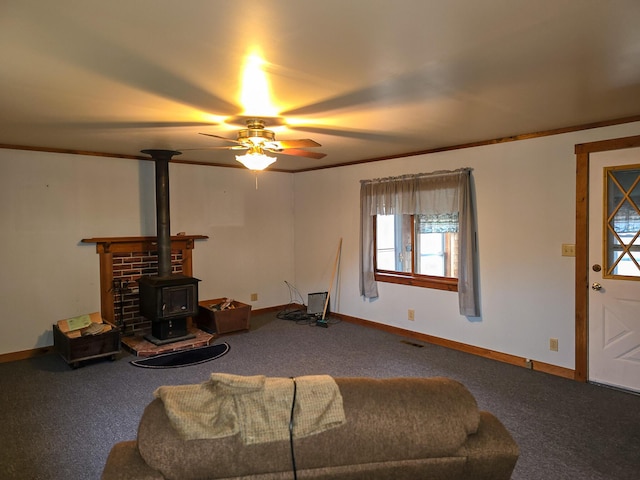 living room featuring a wood stove, ceiling fan, carpet, and ornamental molding