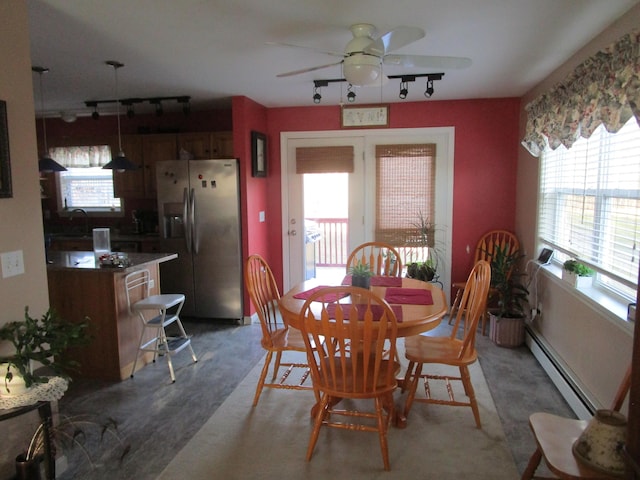 carpeted dining area with ceiling fan, track lighting, and a baseboard heating unit