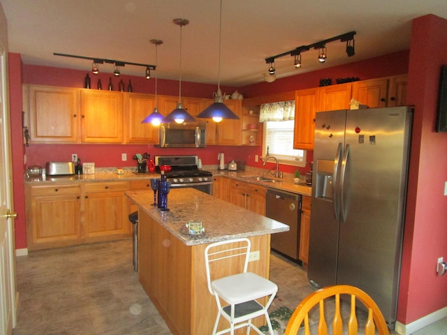 kitchen featuring sink, hanging light fixtures, track lighting, a kitchen island, and appliances with stainless steel finishes