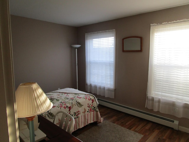 bedroom with baseboard heating, multiple windows, and dark wood-type flooring