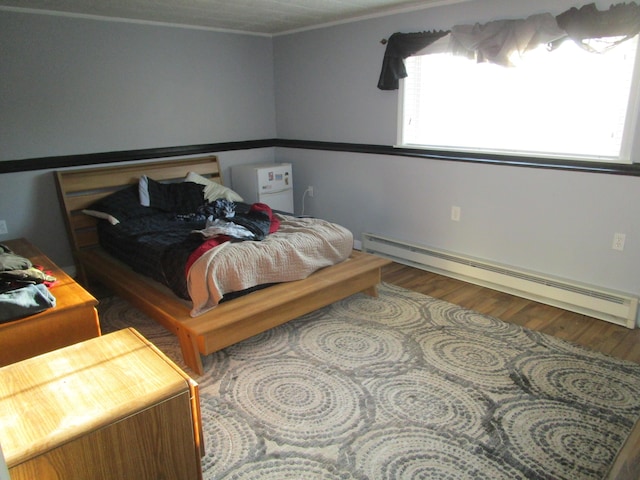 bedroom with hardwood / wood-style floors and a baseboard radiator