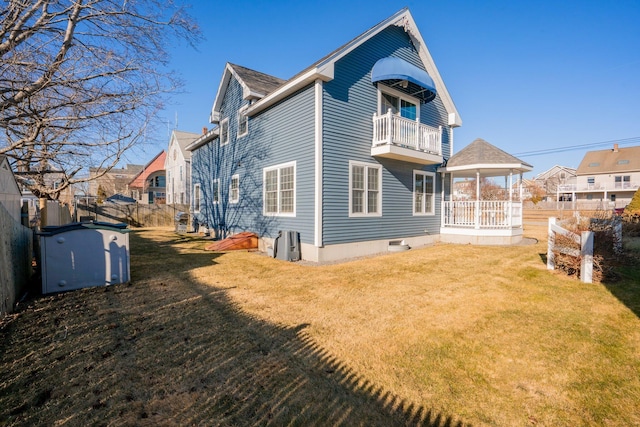 back of house featuring a balcony and a yard