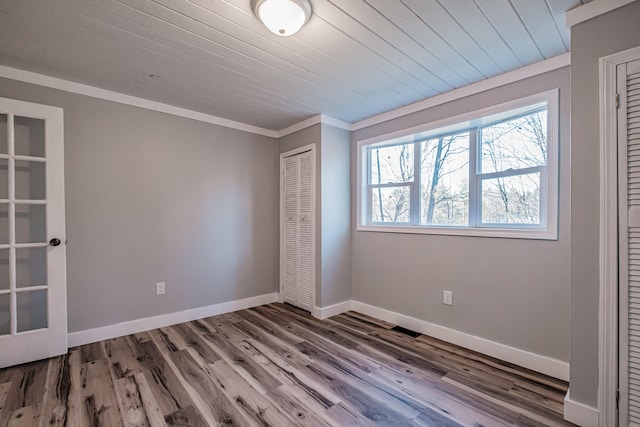 unfurnished bedroom featuring hardwood / wood-style floors, a closet, crown molding, and wood ceiling