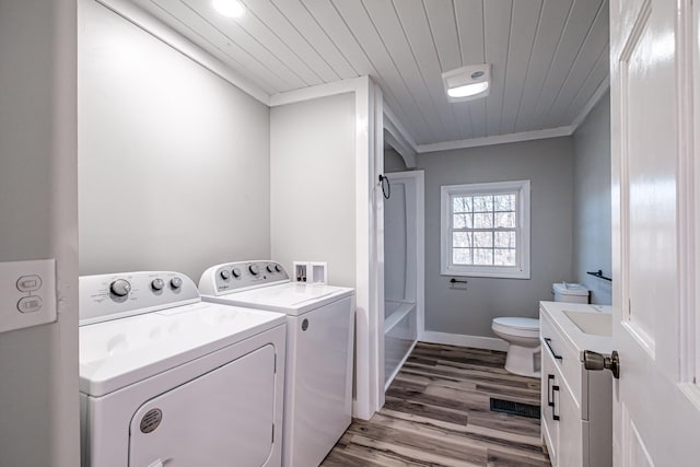 clothes washing area featuring crown molding, washer and clothes dryer, wooden ceiling, and hardwood / wood-style flooring