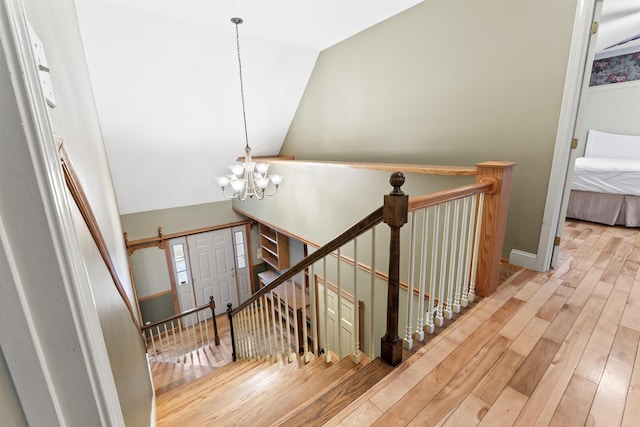 stairs featuring a chandelier, hardwood / wood-style floors, and lofted ceiling