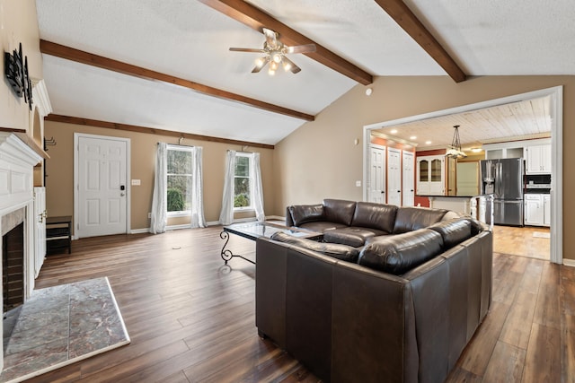 living room with vaulted ceiling with beams, hardwood / wood-style flooring, a brick fireplace, and ceiling fan