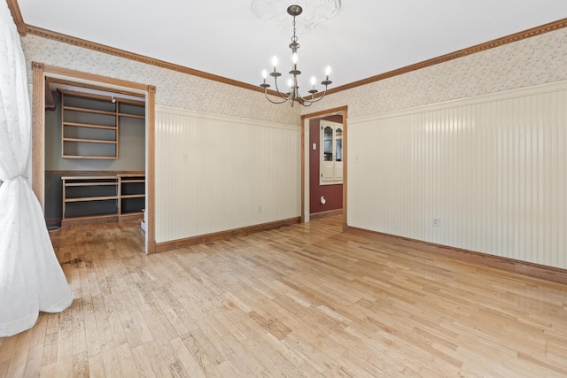 spare room with hardwood / wood-style floors, ornamental molding, and an inviting chandelier