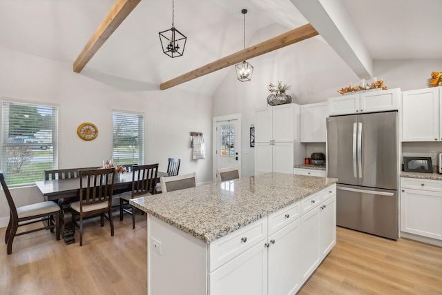 kitchen with lofted ceiling with beams, a center island, white cabinetry, hanging light fixtures, and stainless steel refrigerator