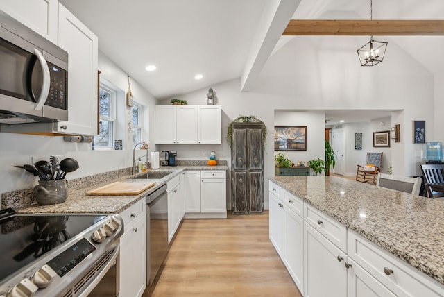 kitchen with white cabinetry, sink, vaulted ceiling with beams, decorative light fixtures, and appliances with stainless steel finishes