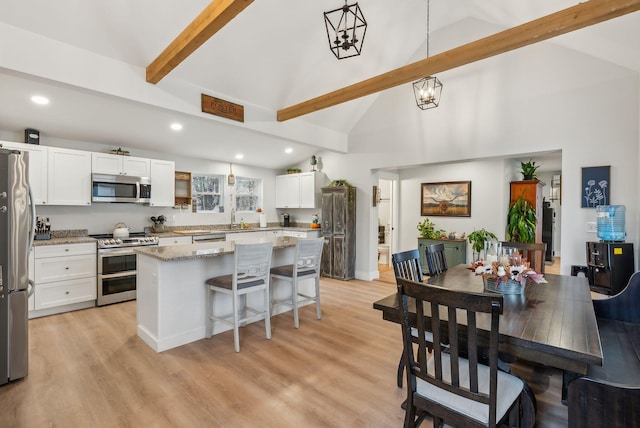 kitchen featuring appliances with stainless steel finishes, a center island, decorative light fixtures, and white cabinetry