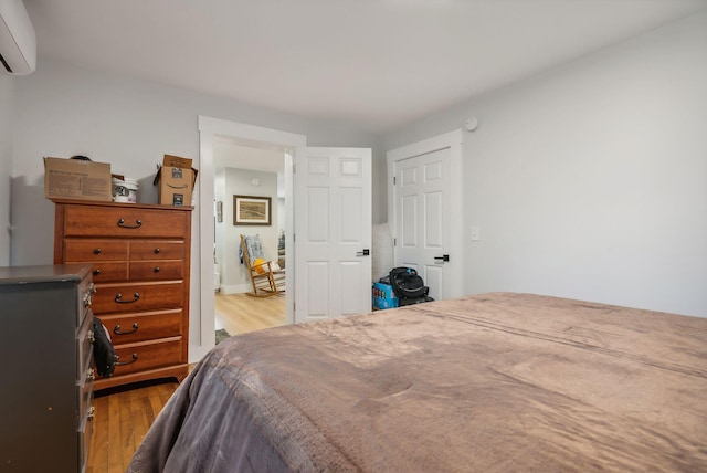 bedroom with light wood-type flooring and a wall unit AC