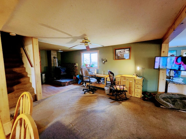 office space featuring carpet flooring, ceiling fan, a wood stove, and a textured ceiling