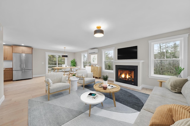 living room featuring light wood-type flooring, a wealth of natural light, and a wall mounted AC