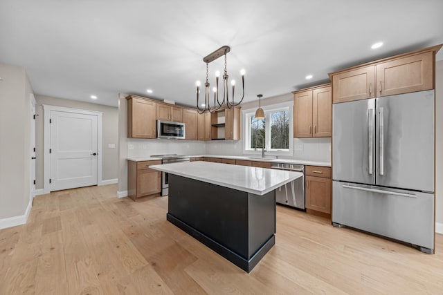 kitchen featuring sink, a center island, hanging light fixtures, appliances with stainless steel finishes, and light wood-type flooring