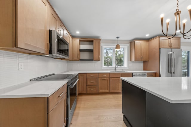 kitchen featuring light wood-type flooring, stainless steel appliances, plenty of natural light, and hanging light fixtures