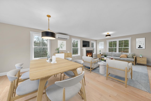 dining area with a wealth of natural light, light hardwood / wood-style floors, and a wall mounted air conditioner