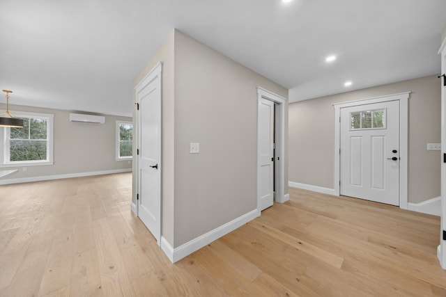 foyer with an AC wall unit and light hardwood / wood-style flooring