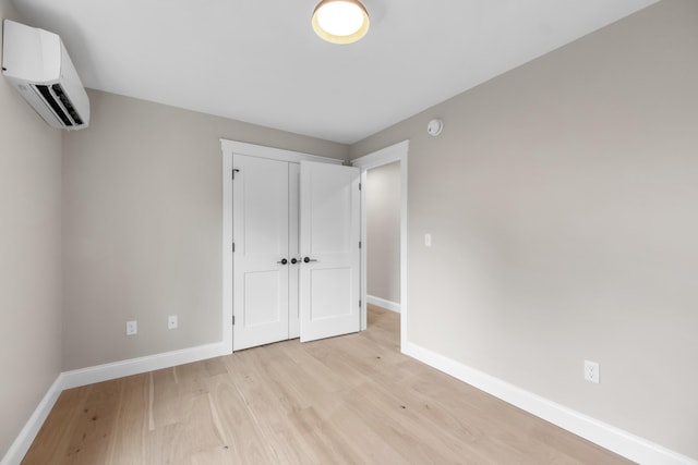 unfurnished bedroom featuring a wall mounted AC and light wood-type flooring