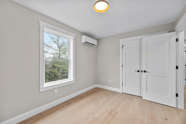 unfurnished bedroom featuring a wall mounted air conditioner, light wood-type flooring, and a closet