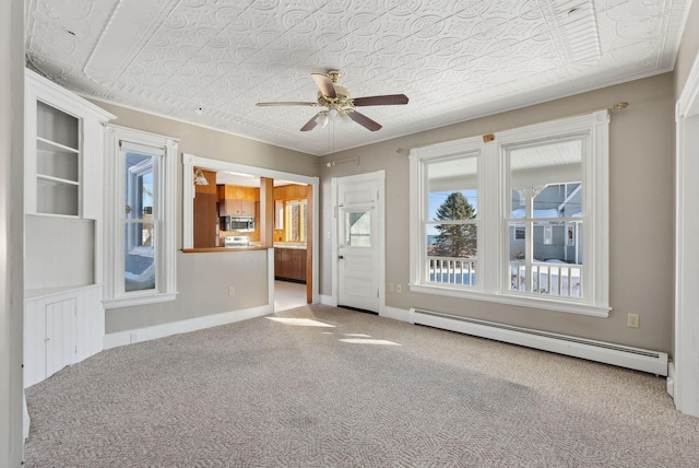 spare room with a baseboard heating unit, ceiling fan, baseboards, carpet, and an ornate ceiling