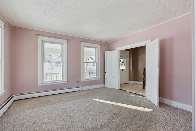 carpeted spare room featuring a baseboard heating unit and baseboards