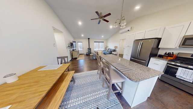 kitchen featuring white cabinets, a kitchen bar, stainless steel appliances, and dark stone countertops