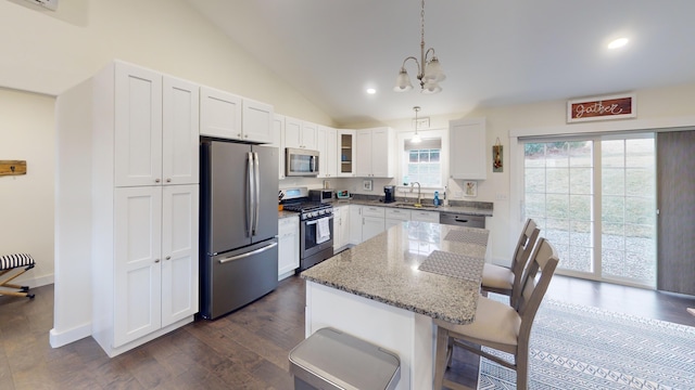 kitchen featuring pendant lighting, appliances with stainless steel finishes, stone countertops, a kitchen island, and white cabinetry