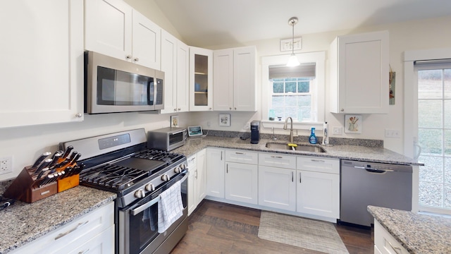 kitchen with sink, hanging light fixtures, stainless steel appliances, light stone counters, and white cabinets