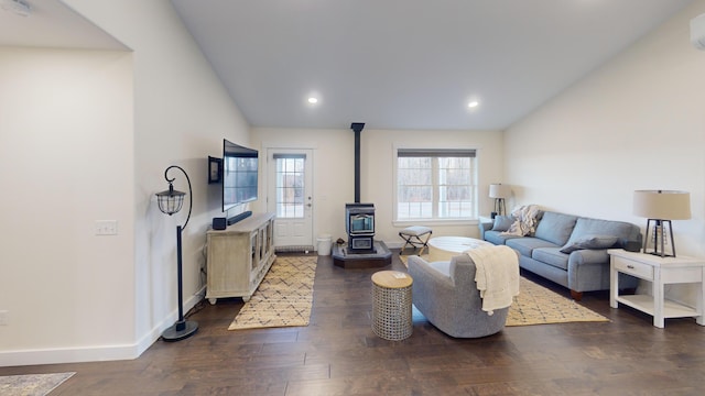 living room with dark hardwood / wood-style floors, a wood stove, and lofted ceiling