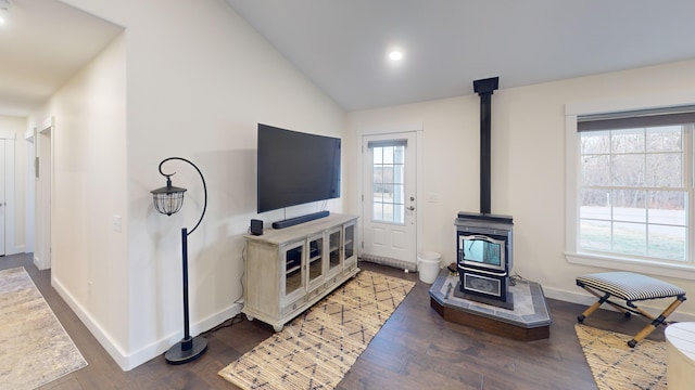 living room with wood-type flooring, a wood stove, and vaulted ceiling