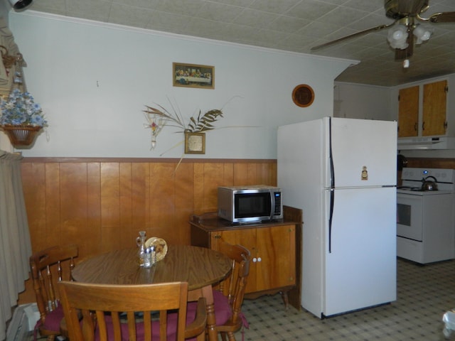 kitchen with ceiling fan, white appliances, ornamental molding, and wooden walls