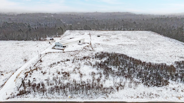 snowy aerial view featuring a forest view