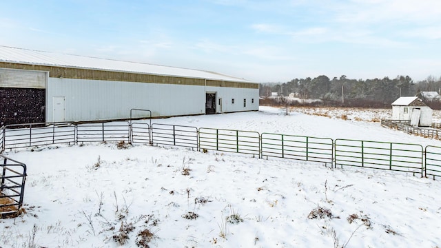 snowy yard featuring a garage, fence, and an outbuilding