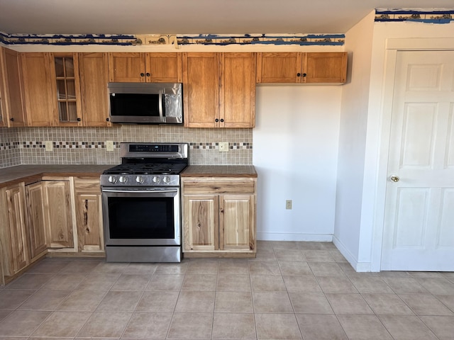 kitchen with tasteful backsplash, stainless steel appliances, and light tile patterned flooring