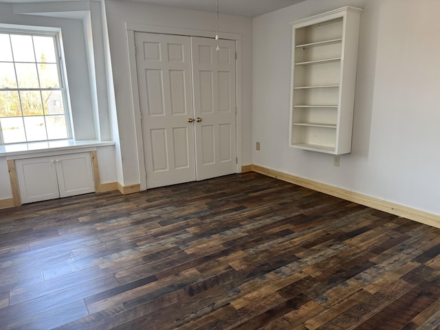 unfurnished bedroom with baseboards, dark wood finished floors, and a closet