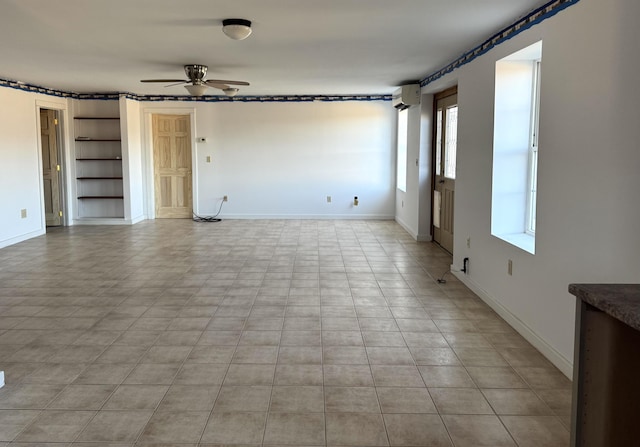 empty room with a wall mounted air conditioner, built in features, and ceiling fan