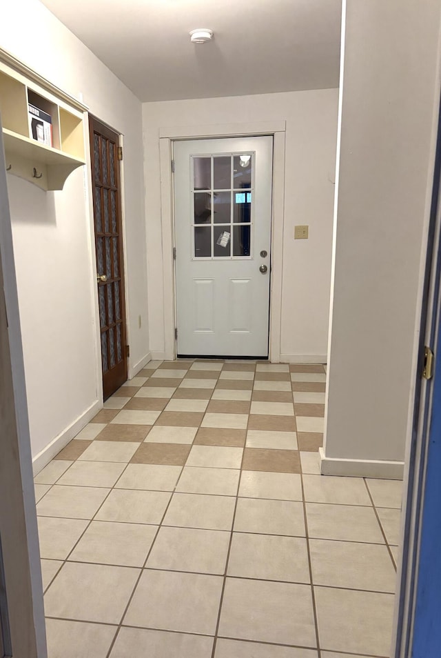 doorway featuring light tile patterned floors and baseboards