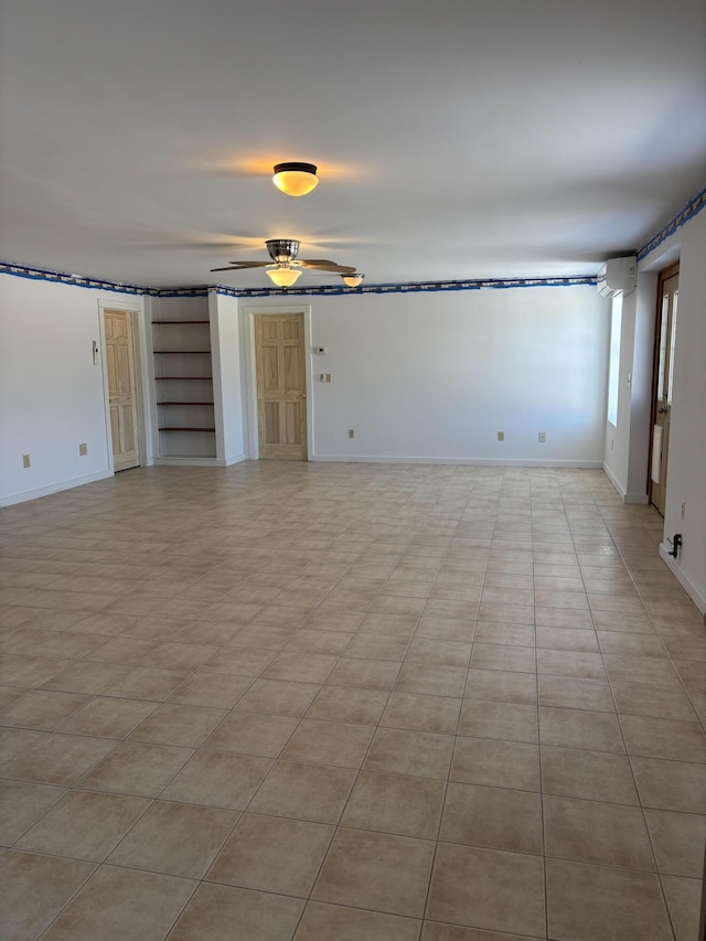 unfurnished living room featuring a ceiling fan, an AC wall unit, built in features, and baseboards