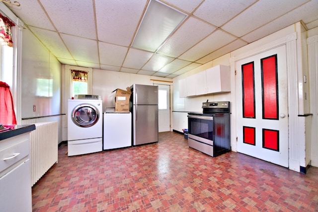 kitchen featuring a paneled ceiling, washer and clothes dryer, radiator, appliances with stainless steel finishes, and white cabinetry