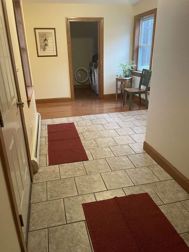 corridor with washer / clothes dryer and a baseboard heating unit