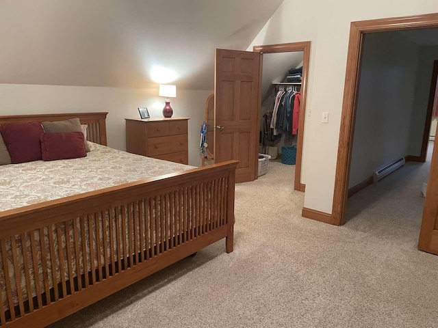 carpeted bedroom with a walk in closet, a closet, lofted ceiling, and a baseboard heating unit