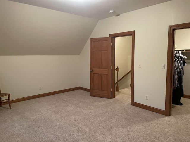 bonus room with light colored carpet and vaulted ceiling