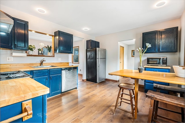 kitchen featuring blue cabinetry, appliances with stainless steel finishes, butcher block countertops, and sink