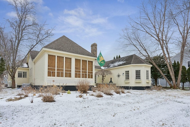 snow covered back of property with a sunroom