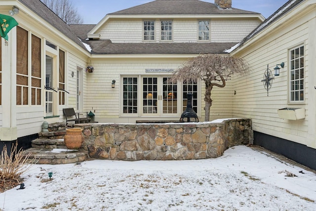 snow covered rear of property with french doors