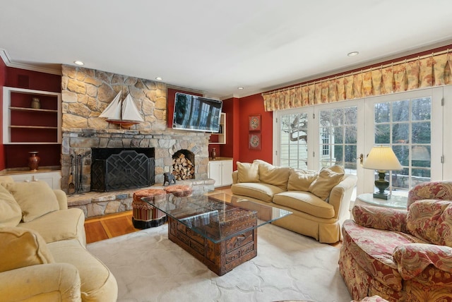 living room with a stone fireplace, ornamental molding, and light hardwood / wood-style flooring