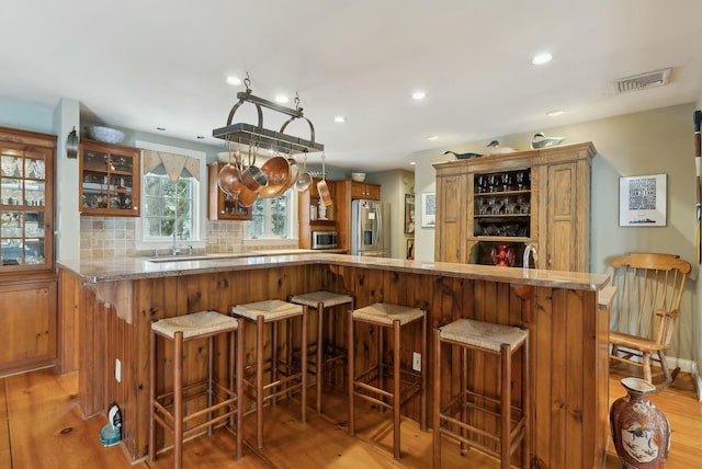 bar with backsplash, stainless steel appliances, and hardwood / wood-style floors