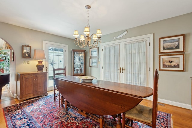 dining area with french doors, a notable chandelier, and light hardwood / wood-style flooring