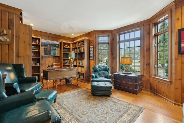 sitting room featuring wood walls, a healthy amount of sunlight, and light hardwood / wood-style flooring